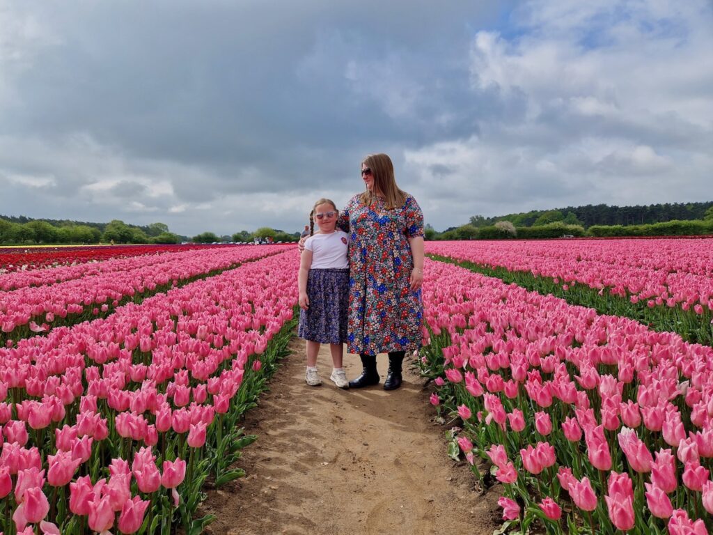 Mum and 7 year old daughter standing in a field of pink tulips