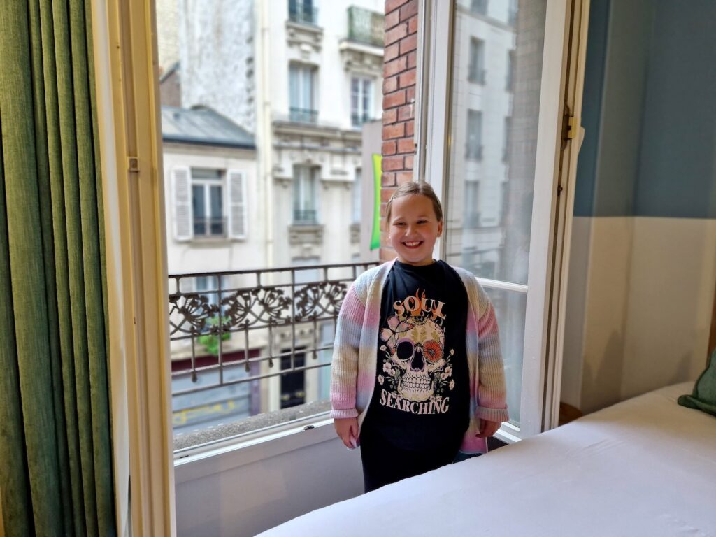 7 year old girl standing in front of large windows at ibis Styles Paris Montmartre Nord