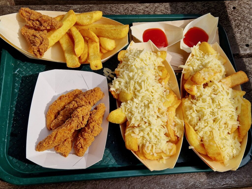 Children's chicken goujons and chips, a tray of chicken goujons and 2 trays of cheesy chips on a green food tray. 