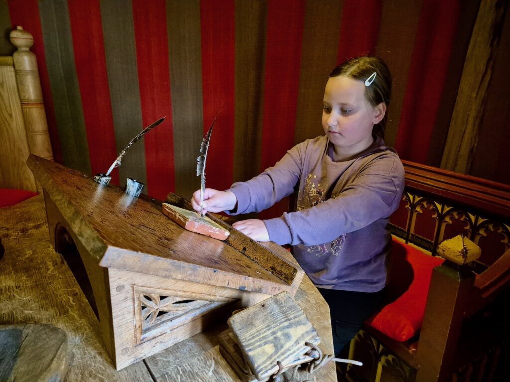 Erin learning to write with a quill at Barley Hall