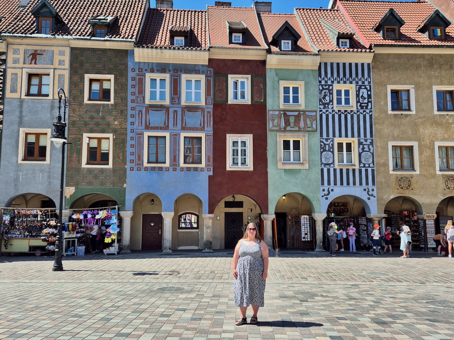 Me, stood in Poznan's market square in front of a row of colourful buildings