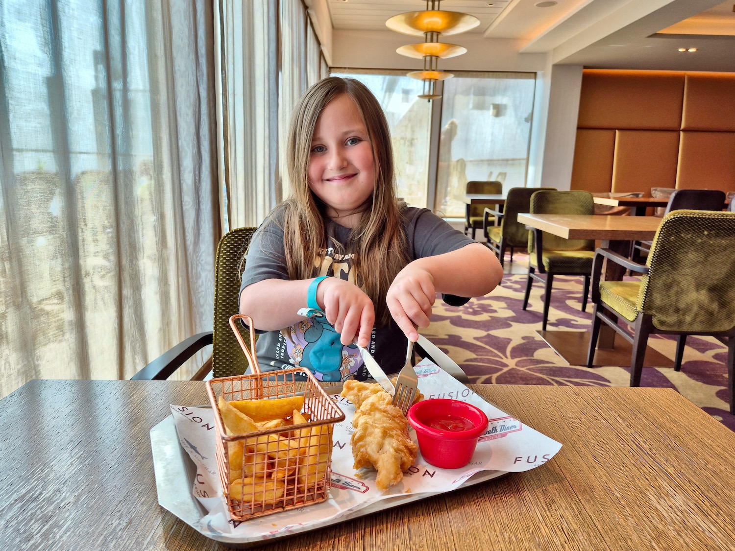 Erin eating fish and chips from The Quays on P&O Iona