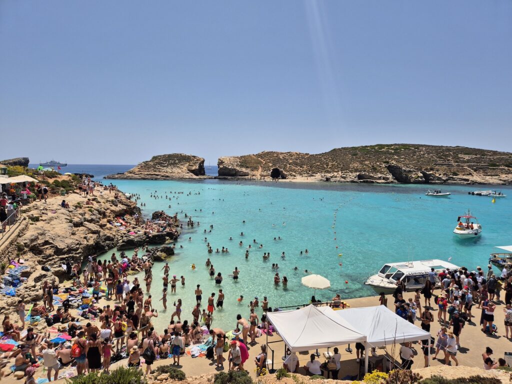 Crowds enjoying the crystal-clear waters of the Blue Lagoon in Comino, Malta on a sunny summer day
