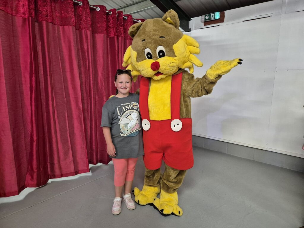 Child posing with the Go Awesome mascot in red dungarees at Banham Zoo