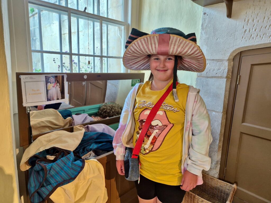 Child wearing a large Georgian-style hat inside the dressing-up area at No. 1 Royal Crescent Bath