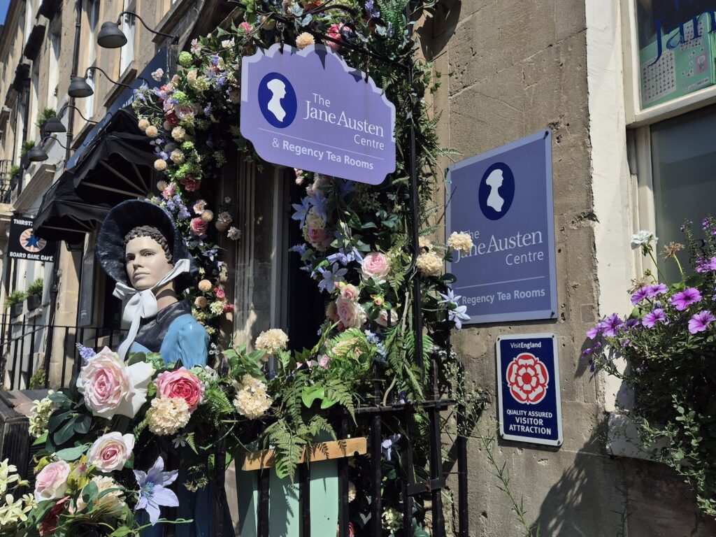 Jane Austen statue and floral display outside the entrance to the Jane Austen Centre in Bath