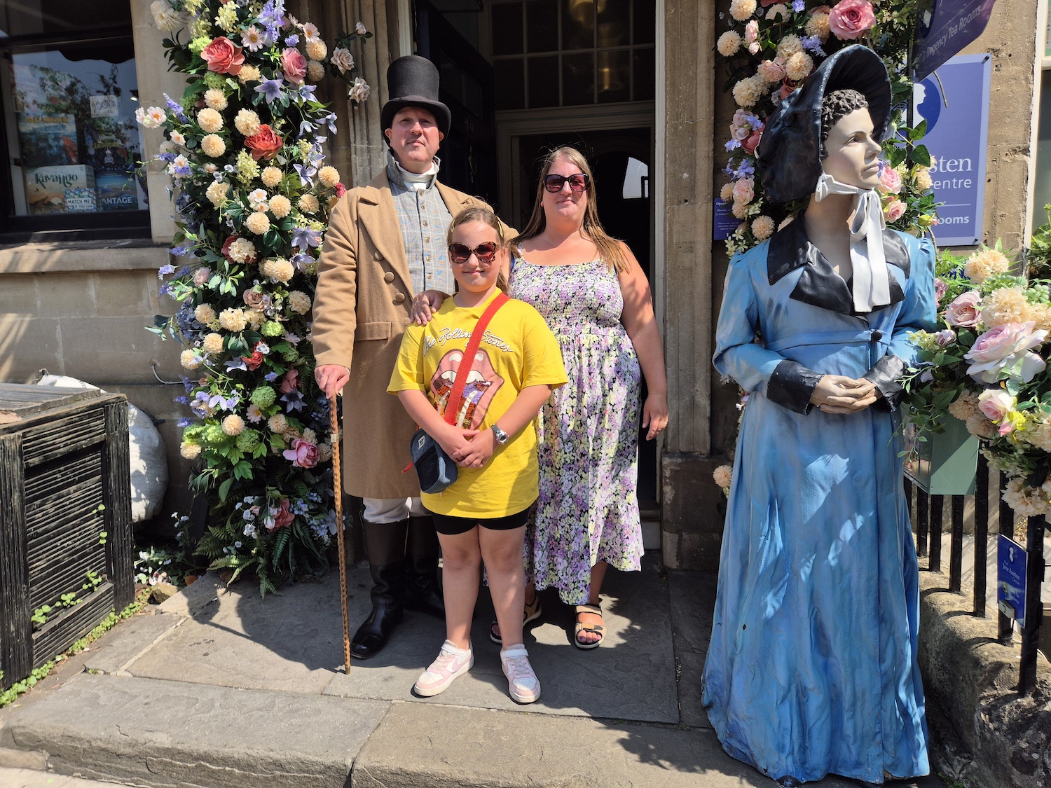 Family standing with a costumed guide outside the Jane Austen Centre in Bath, next to a Jane Austen statue
