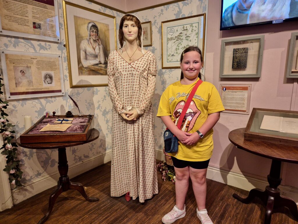 Child standing beside a wax figure of Jane Austen at the Jane Austen Centre in Bath